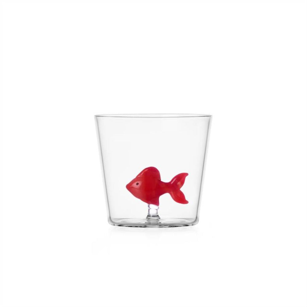 Vaso transparente con un pez rojo en el interior, forma redondeada y lisa, ambiente neutro.