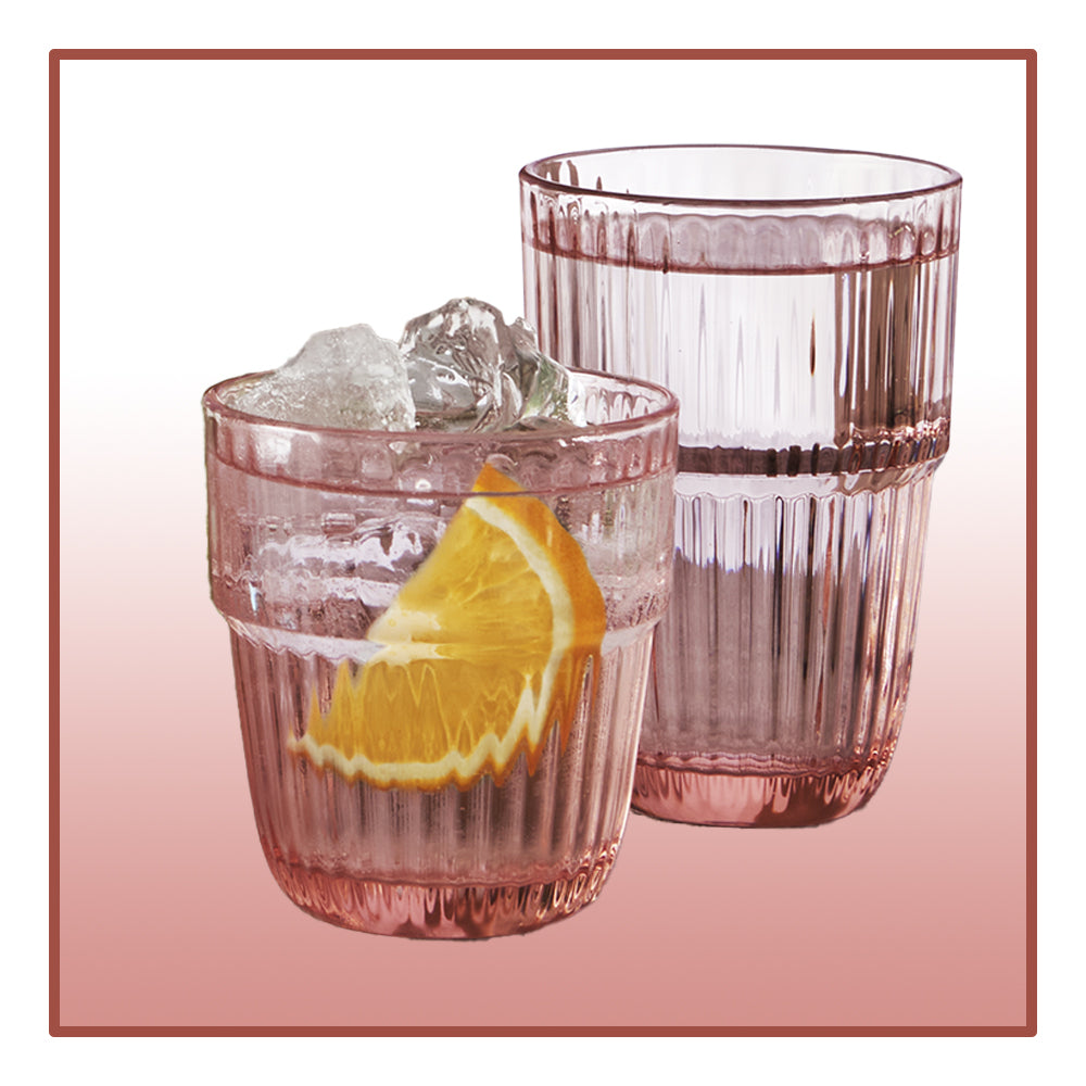 due bicchieri rosa trasparente in vetro scanalato, uno con acqua e fetta di arancia, l'altro con acqua e