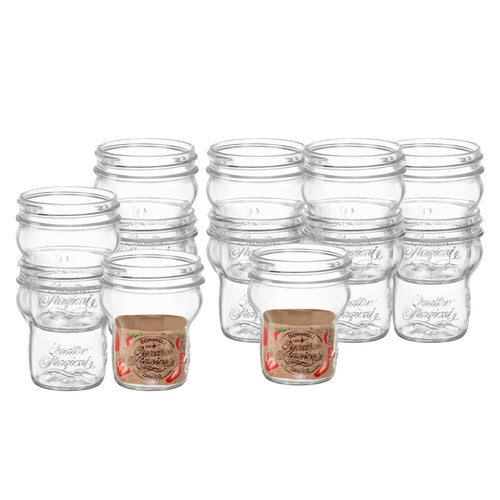 Acht transparente Glasgefäße mit erhabener Schrift, zwei mit braunem Etikett für Waldbeermarmelade, ohne Deckel.