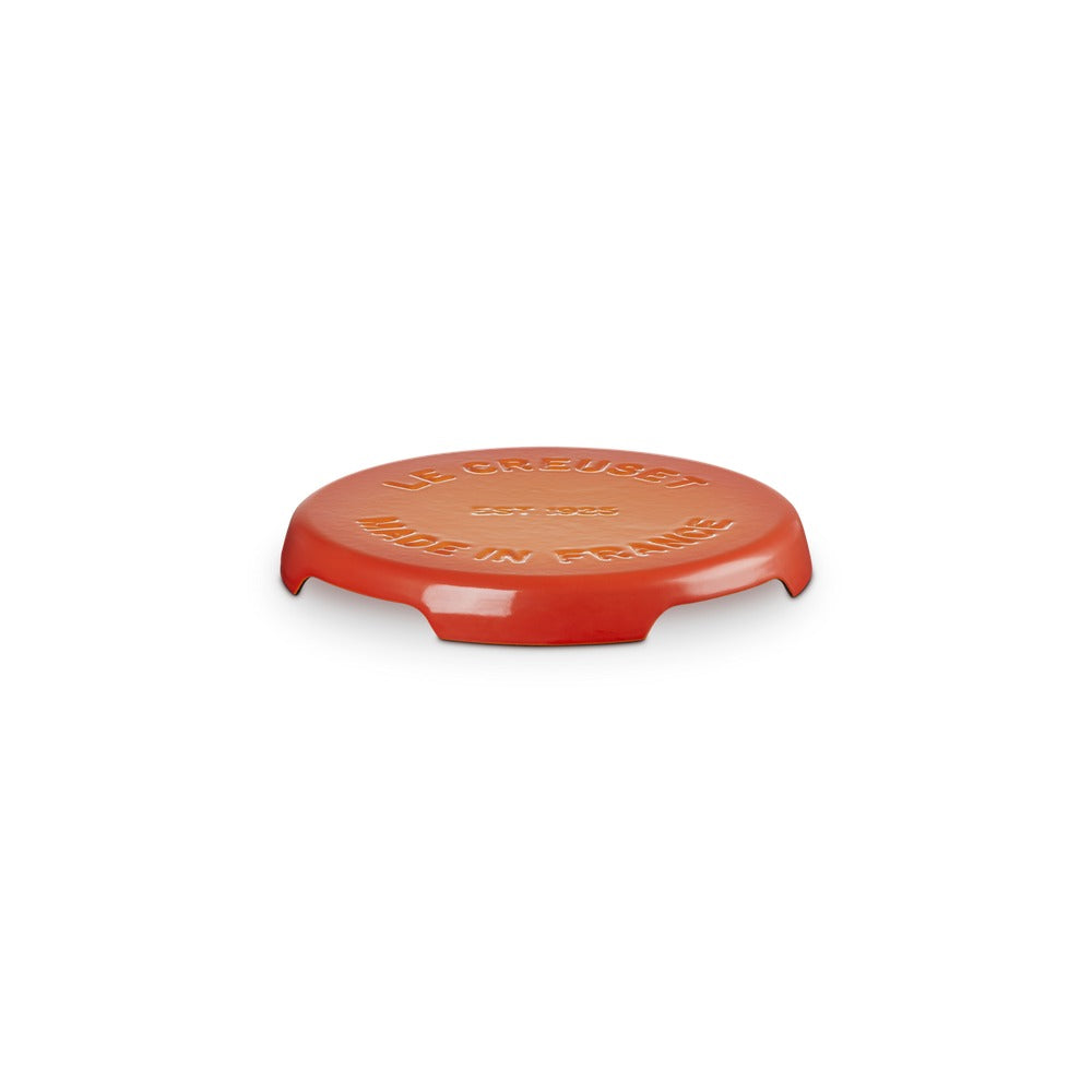 Coperchio circolare di colore rosso lucido con scritte dorate, in materiale ceramico, su sfondo bianco.