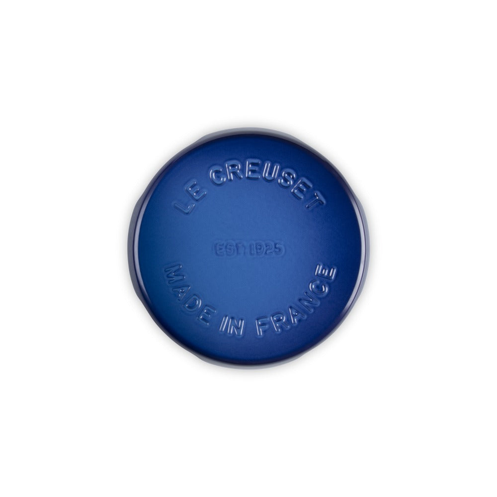 Rivestimento blu di un oggetto rotondo con le scritte "LE CREUSET" e "MADE IN FRANCE" in rilievo, su sfondo bianco.