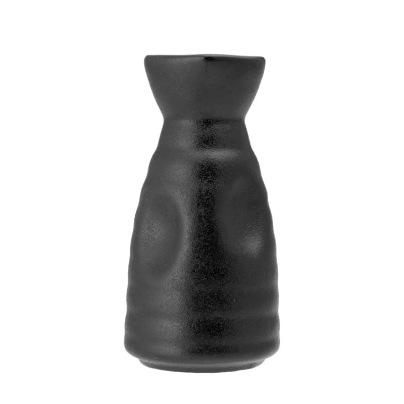 Botella negra opaca de forma ligeramente irregular con base más ancha y cuello estrecho, sobre fondo blanco.