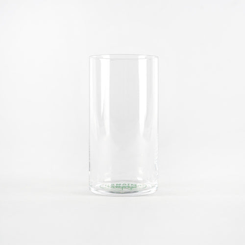 Transparentes zylindrisches Glas mit grünem Logo auf der Basis. Einheitlicher weißer Hintergrund.
