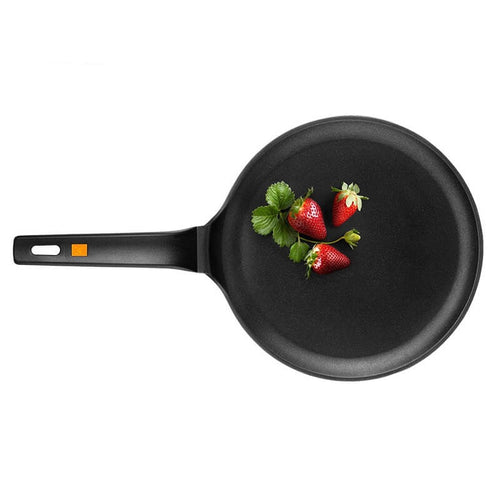 Poêle noire avec manche en plastique, avec fraises fraîches et feuilles vertes au centre.