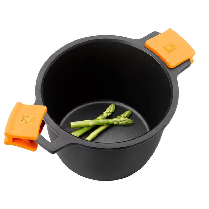 Casserole noire avec anses orange, contenant des asperges vertes fraîches, sur fond neutre.