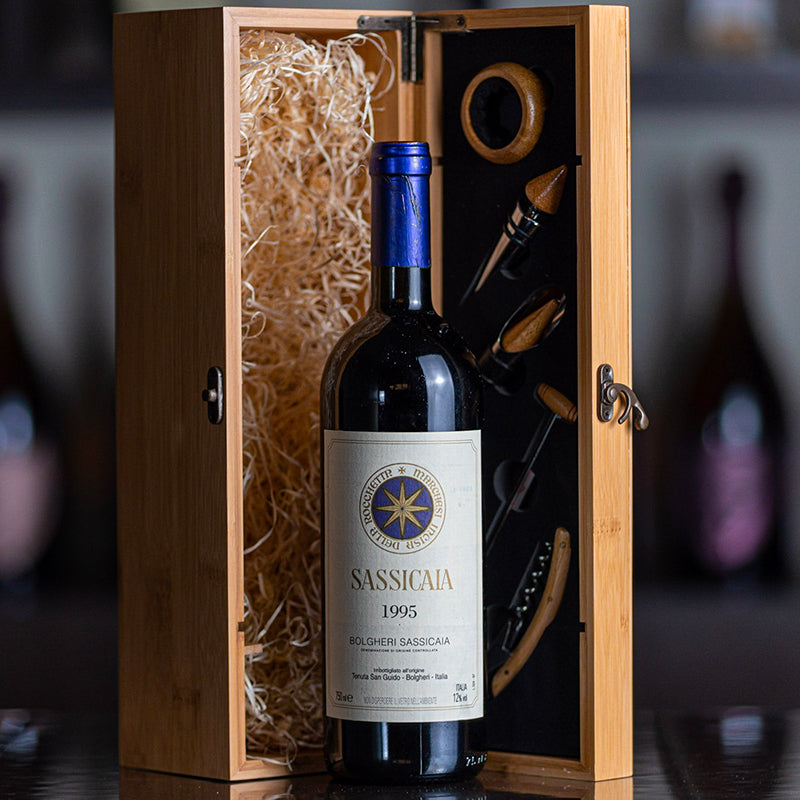 Botella de vino tinto Sassicaia 1995 en vidrio con tapón azul, en caja de madera con accesorios de vino y