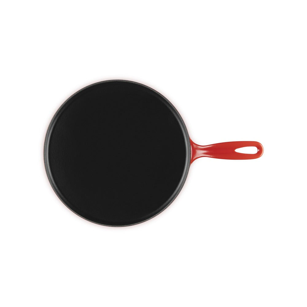 Padella rotonda nera con manico rosso, design semplice, superficie liscia e opaca, fondo piatto.