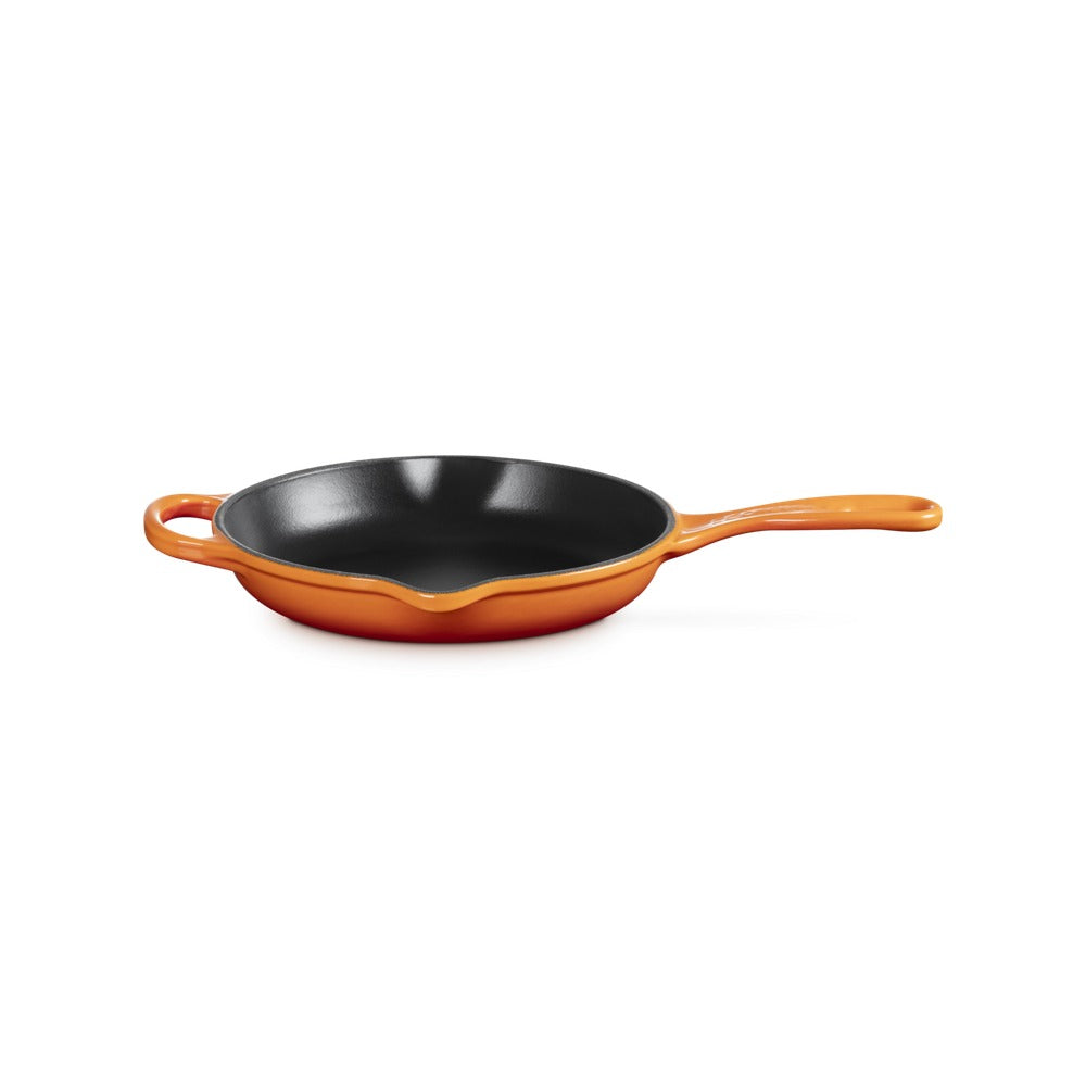 Poêle avec manche orange et intérieur noir, matériau émaillé ; forme ronde avec bord surélevé et deux poignées.