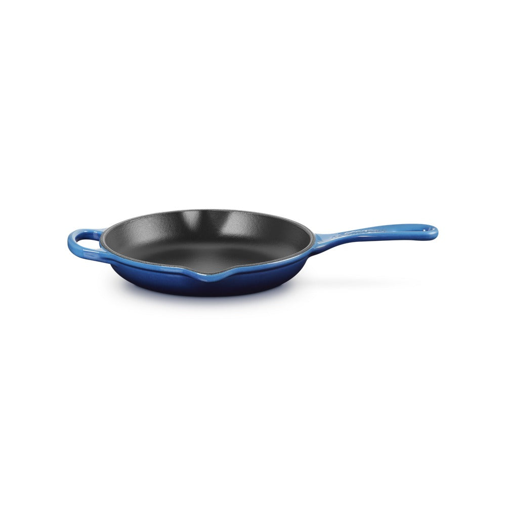 Poêle en fonte émaillée, couleur bleue, avec manche et deux oreilles, surface intérieure noire. Environnement neutre.