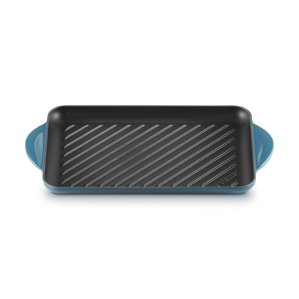 Teglia rettangolare blu con scanalature interne, maniglie ai lati, superficie nera antiaderente.
