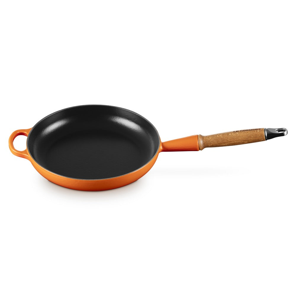 Poêle ronde avec intérieur noir et extérieur orange, manche en bois avec détail métallique. Fond plat et large.