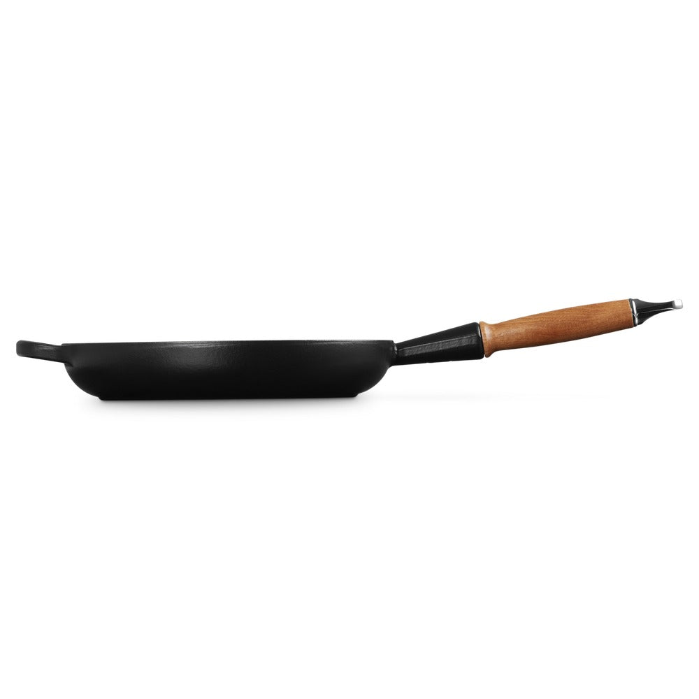 Zwarte koekenpan met houten handgreep, ronde vorm en hoge randen, op witte achtergrond.