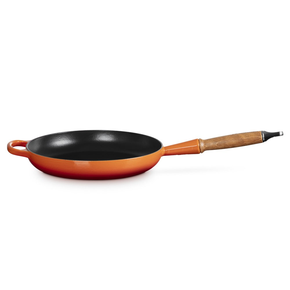 Koekenpan met houten handgreep, zwarte bodem en oranje lichaam, op witte achtergrond.