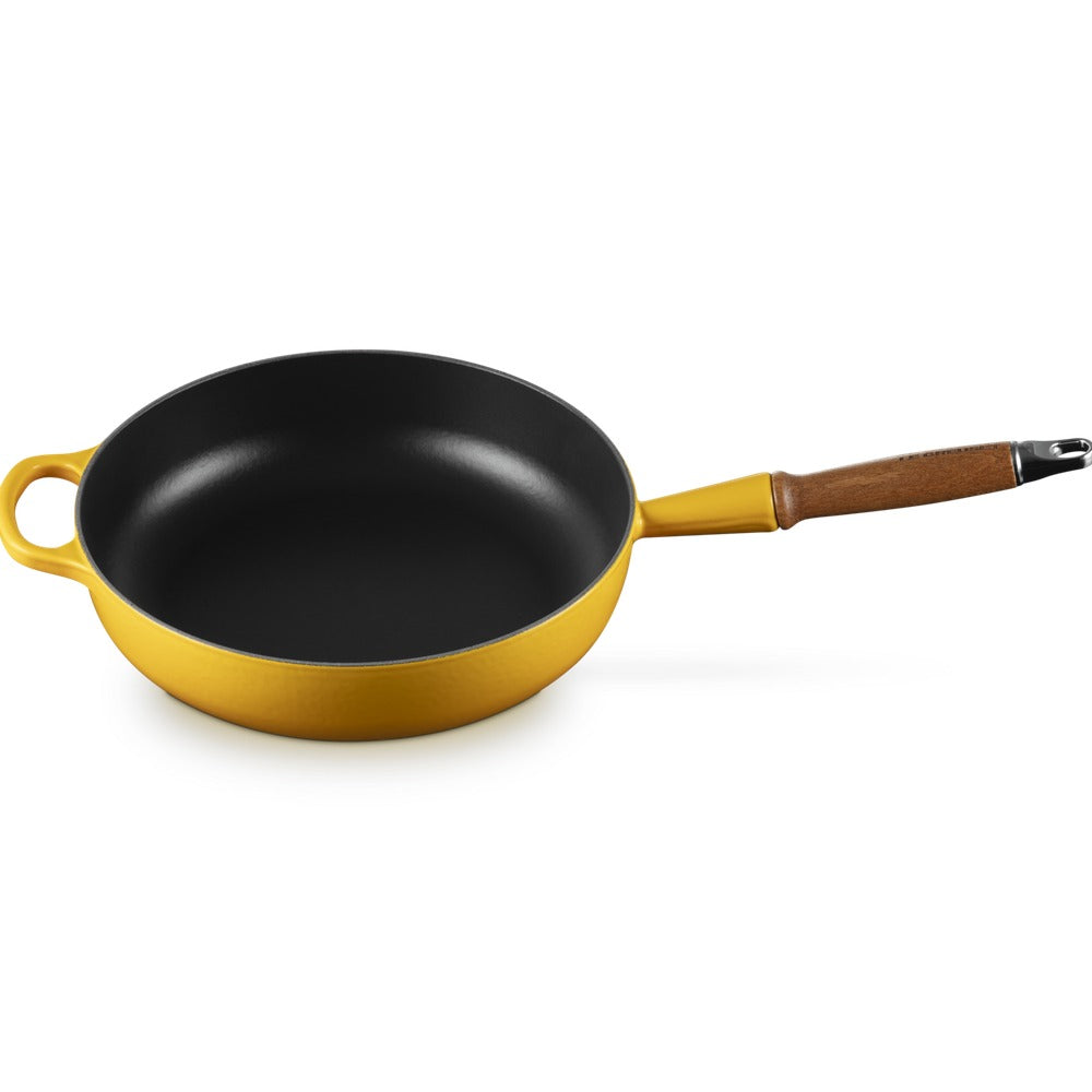 Padella circolare gialla con manico in legno e rivestimento interno nero, su sfondo bianco.