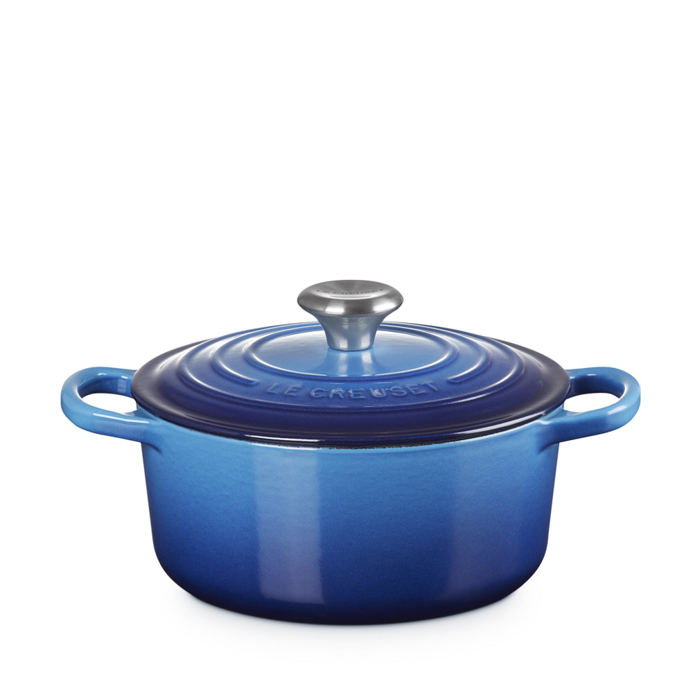 Pentola ovale in ghisa smaltata blu con coperchio, maniglie laterali e pomello in metallo, marchio Le Creuset inciso sul coperchio.