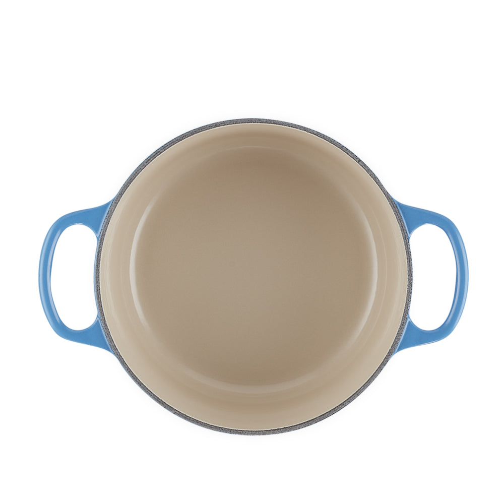 Pentola tonda doppio manico smaltata beige all'interno e blu all'esterno, vista dall'alto su fondo bianco.
