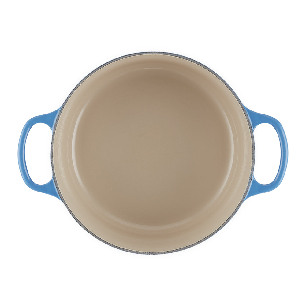 pentola rotonda con manici azzurri in smalto beige all'interno, vista dall'alto su sfondo bianco