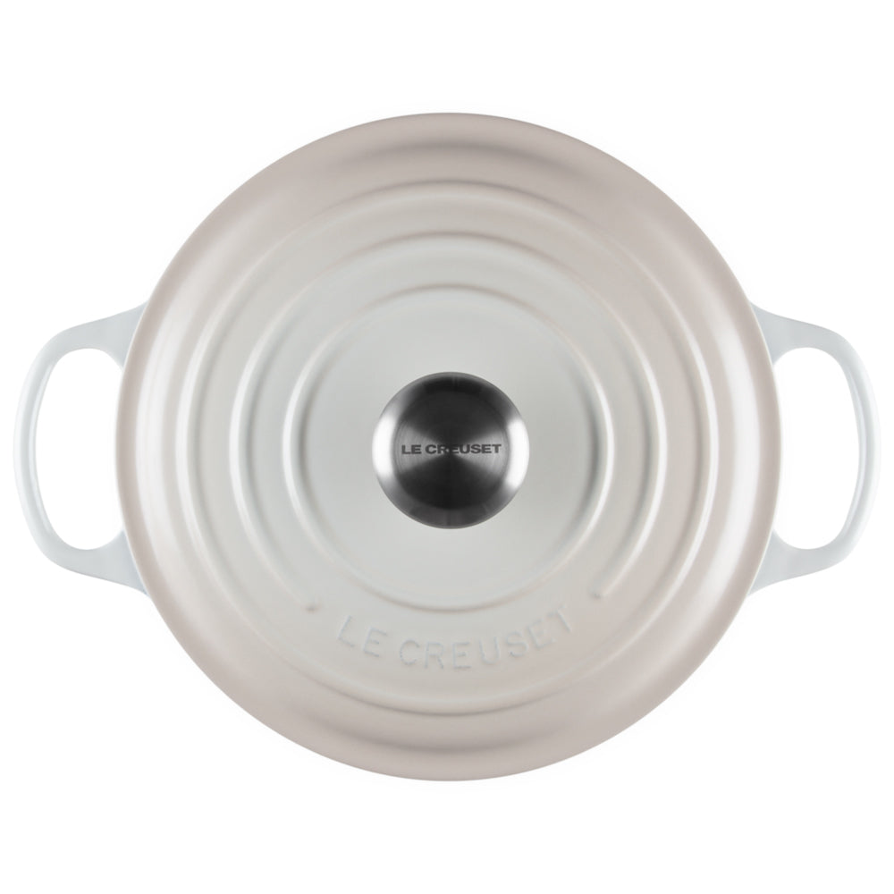 coperchio rotondo color avorio in ghisa smaltata con manici laterali, pomello metallico centrale con scritta Le Creuset, vista dall'alto
