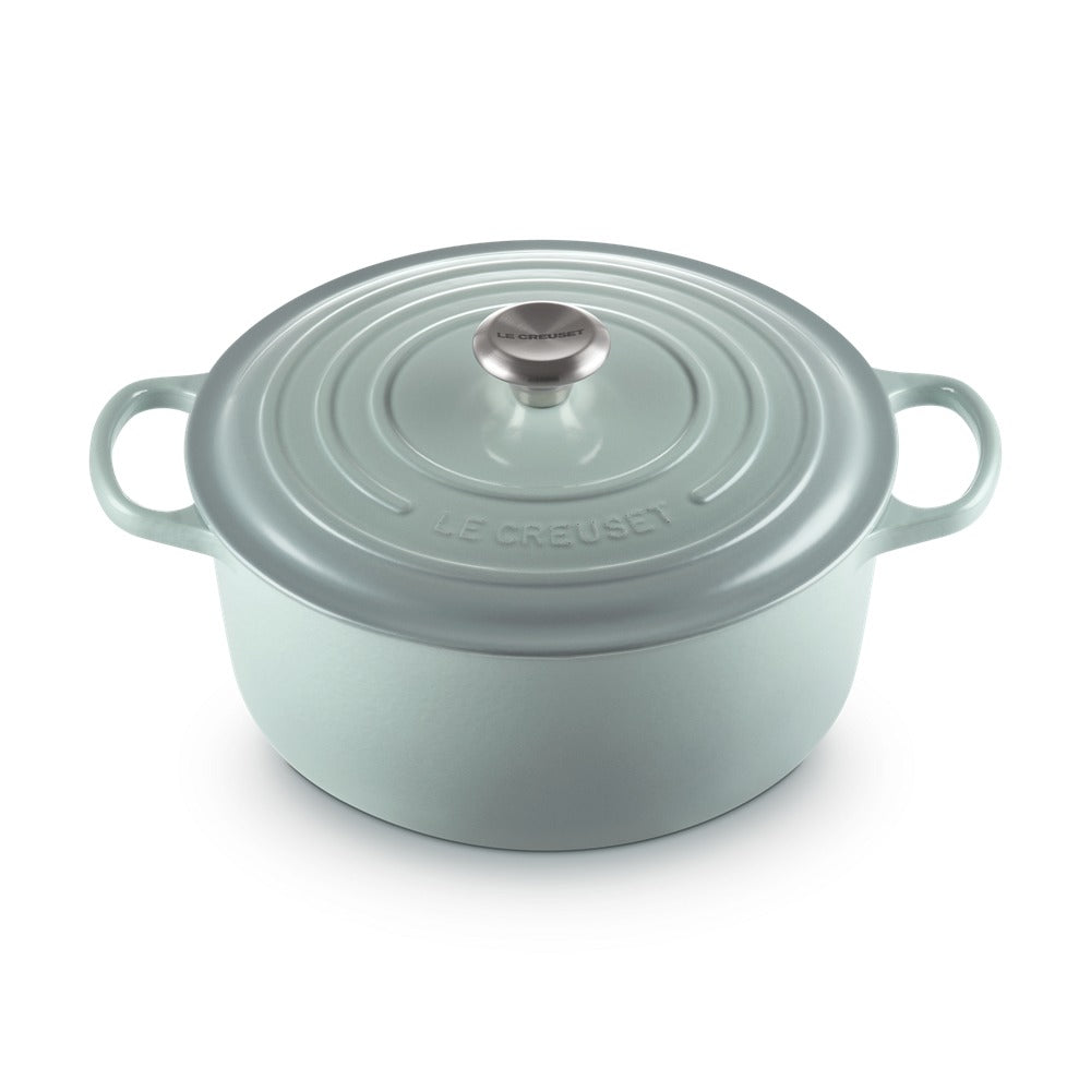 Casseruola di colore verde chiaro con coperchio, manici laterali e pomolo in metallo. Logo "LE CREUSET" in rilievo.