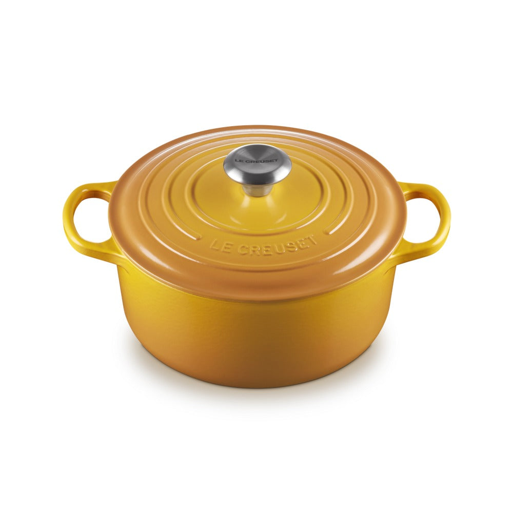 Gele braadpan met deksel en handgrepen, glad oppervlak, reliëf "LE CREUSET"-logo.
