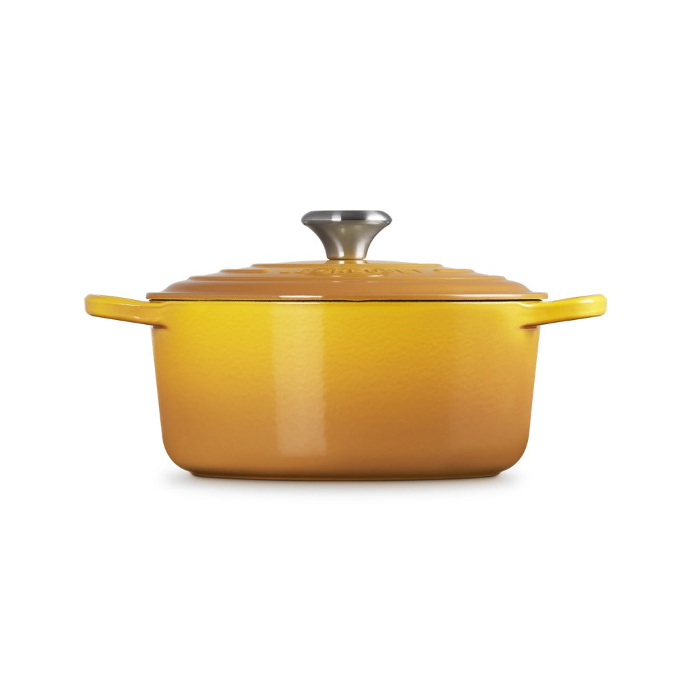 Gele geëmailleerde gietijzeren braadpan met deksel en roestvrijstalen handgreep, op witte achtergrond.