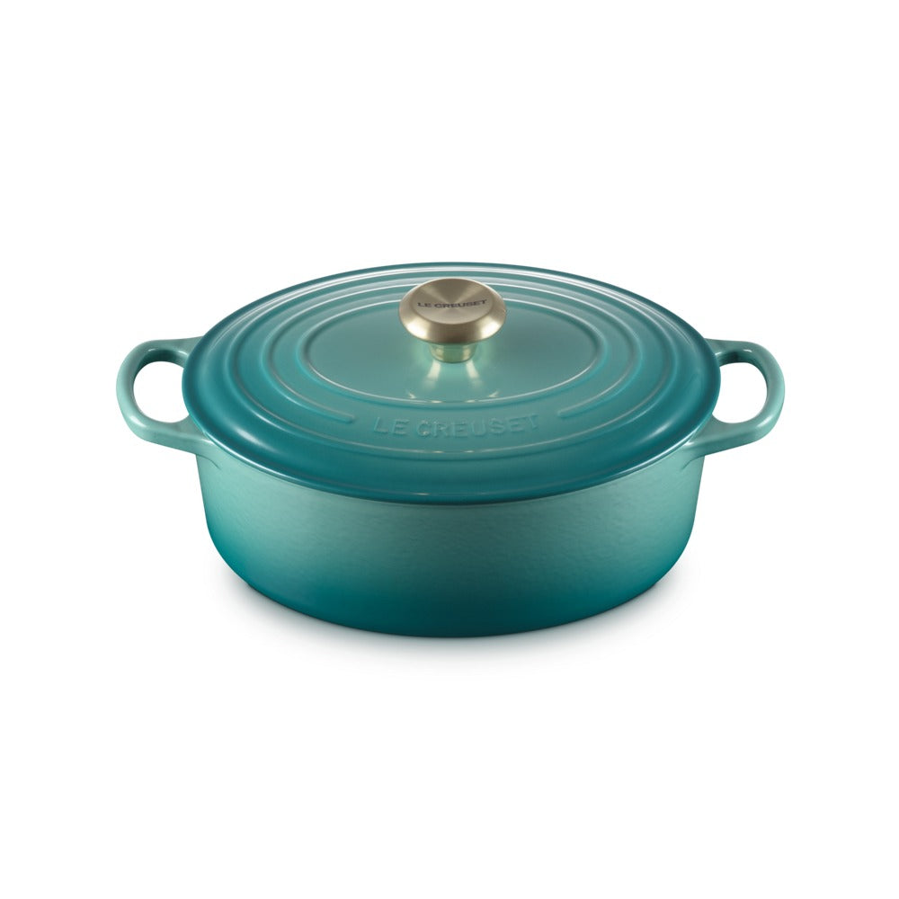 Casserole ovale en fonte émaillée, couleur turquoise, avec couvercle et poignée métallique.