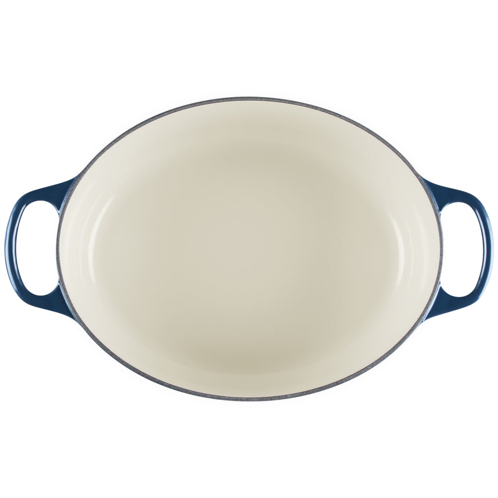 Plat ovale avec poignées bleues extérieures et intérieur émaillé couleur crème, vue de dessus sur fond blanc