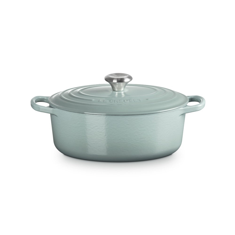 Casserole ovale en fonte émaillée color acqua avec anses et couvercle en métal.
