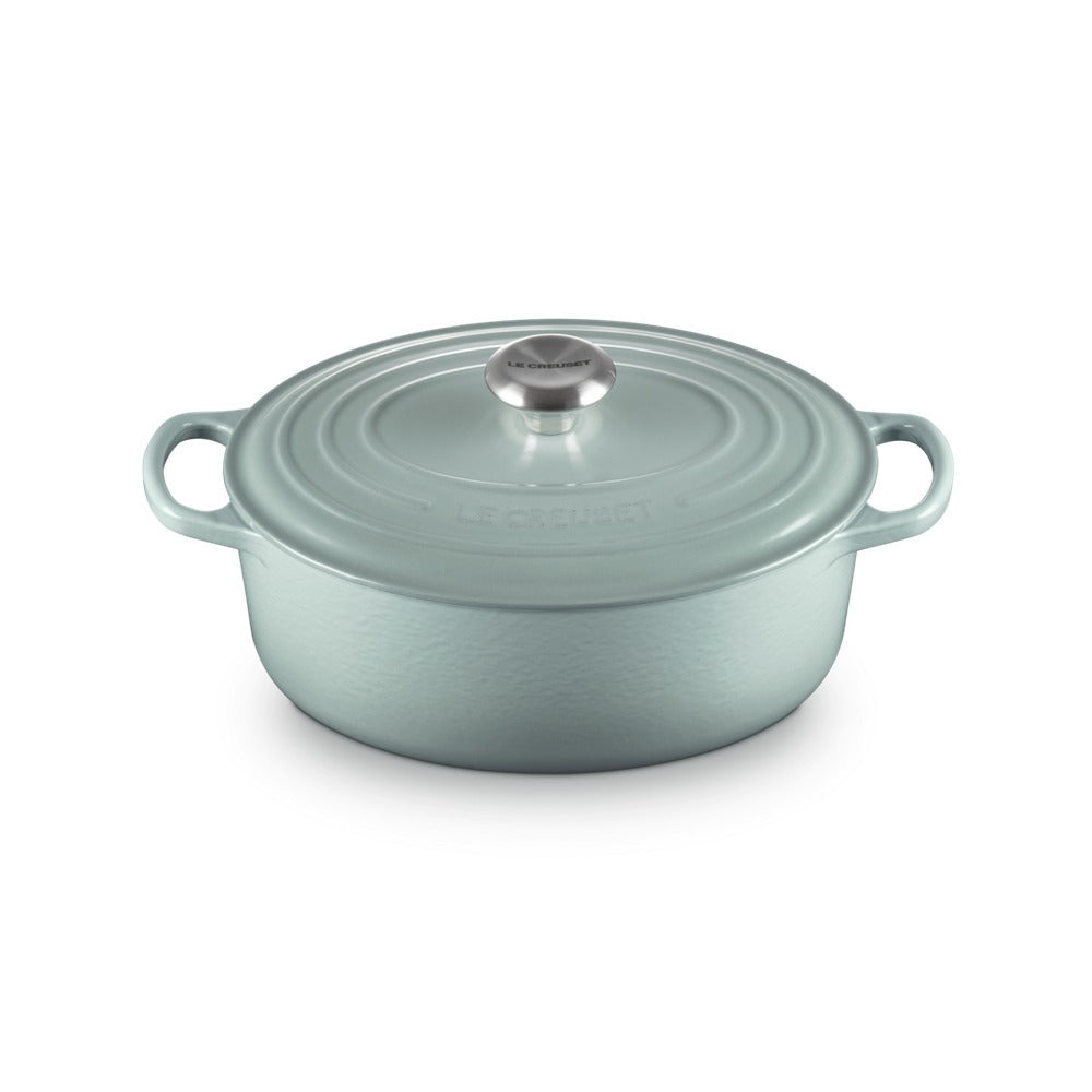 Casserole en fonte émaillée céleste avec couvercle et anses, surface légèrement ondulée et poignée centrale en métal.