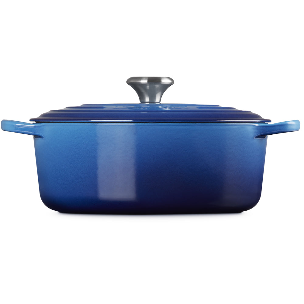 Cocotte rectangulaire en fonte émaillée bleue avec couvercle épais et anses latérales, cuisine studio avec fond blanc