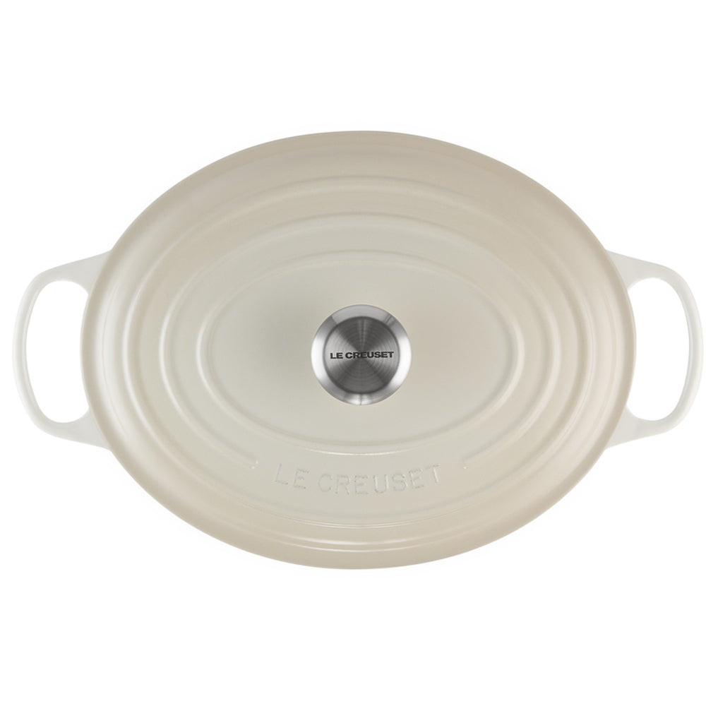 ovaal crèmekleurig geëmailleerd gietijzeren deksel met zijhandvatten en centrale metalen knop met Le Creuset opschrift op witte achtergrond