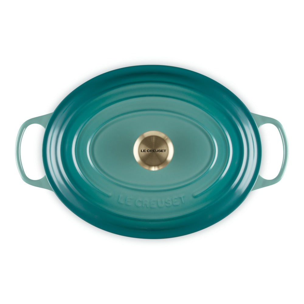ovaal braadpan van keramiek blauw met handgrepen en dekselknop dorato, glanzend oppervlak en opschrift "LE CREUSET" gegraveerd.
