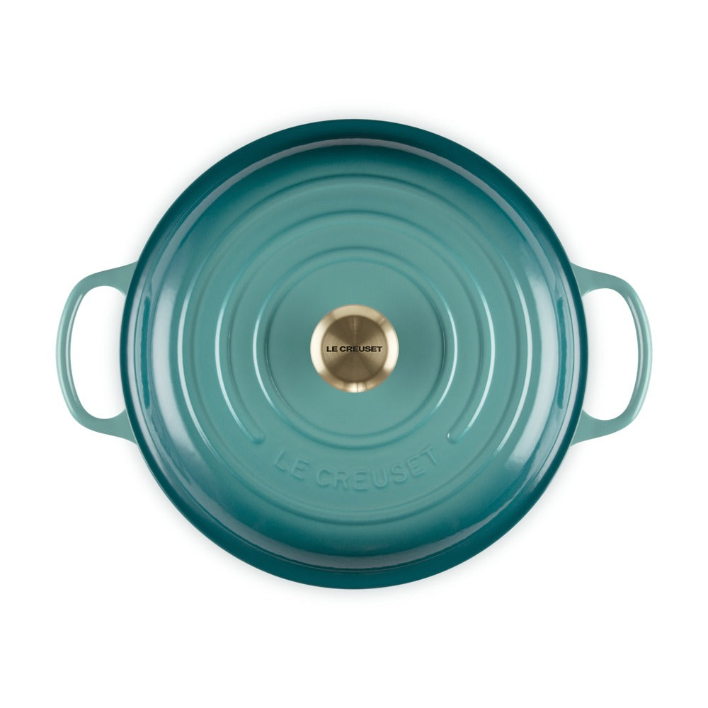 Pentola rotonda in ghisa smaltata di colore verde acqua, con manici laterali e pomolo centrale oro.