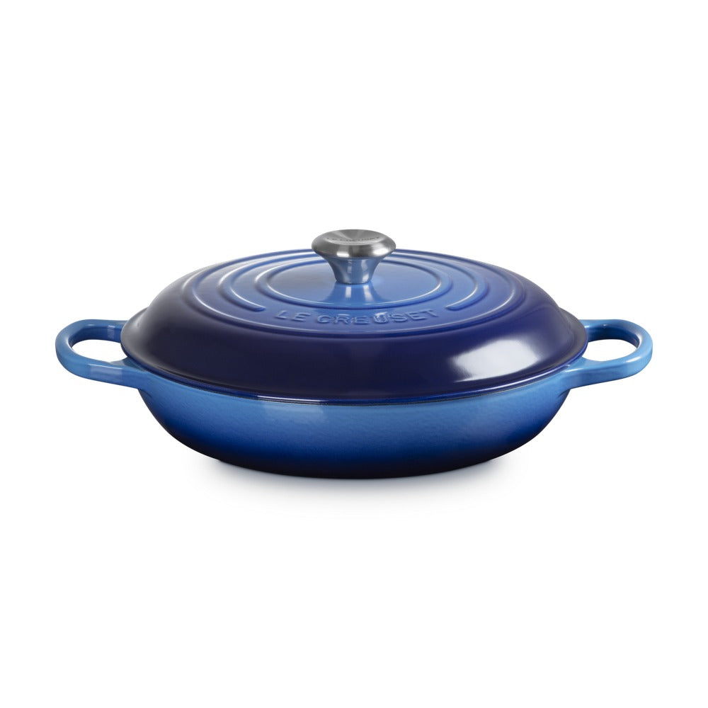 Casseruola ovalizzata in ceramica smaltata blu con coperchio e manici, superficie lucida e fondo cilindrico.