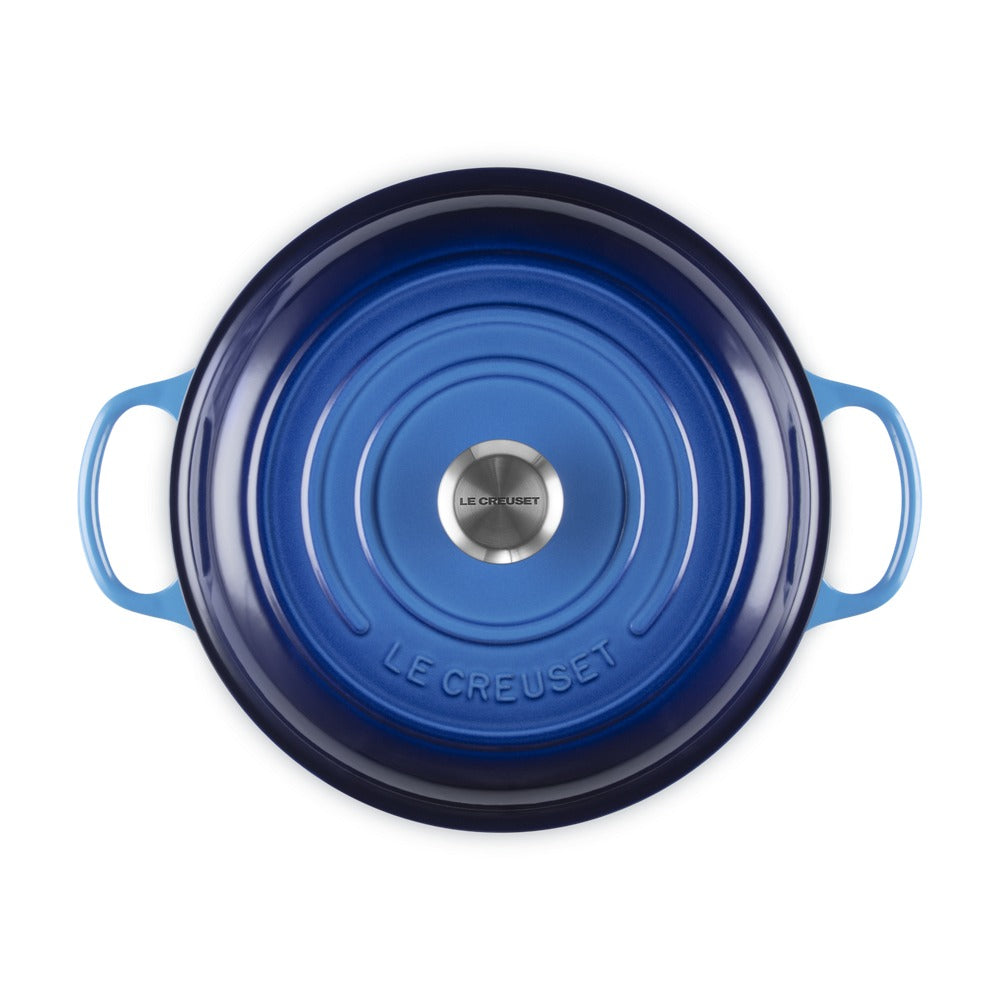 Casseruola in ghisa di colore blu, con manici e superficie liscia; presenta un logo centrale in acciaio inox "LE CREUSET".