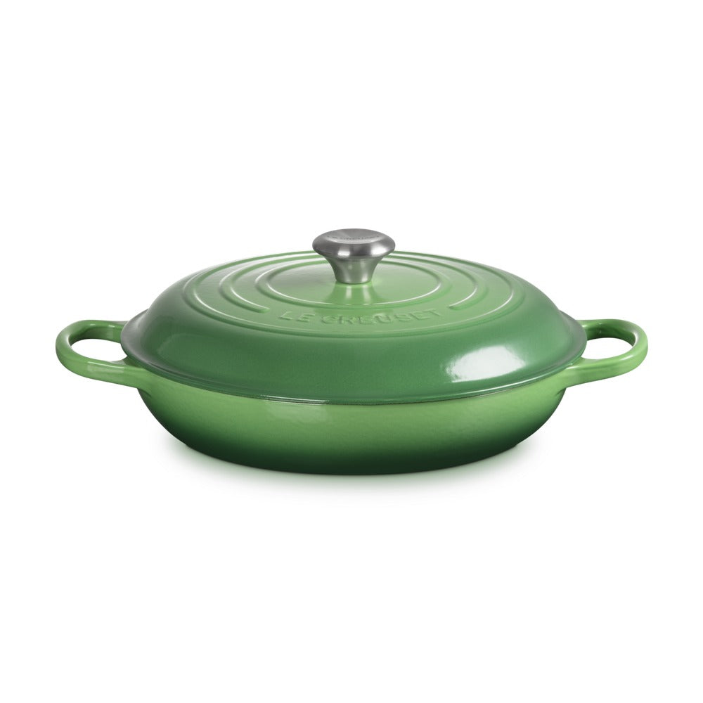Casseruola ovale verde lucido con coperchio e manico in acciaio, con design classico e motivi circolari sulla superficie.