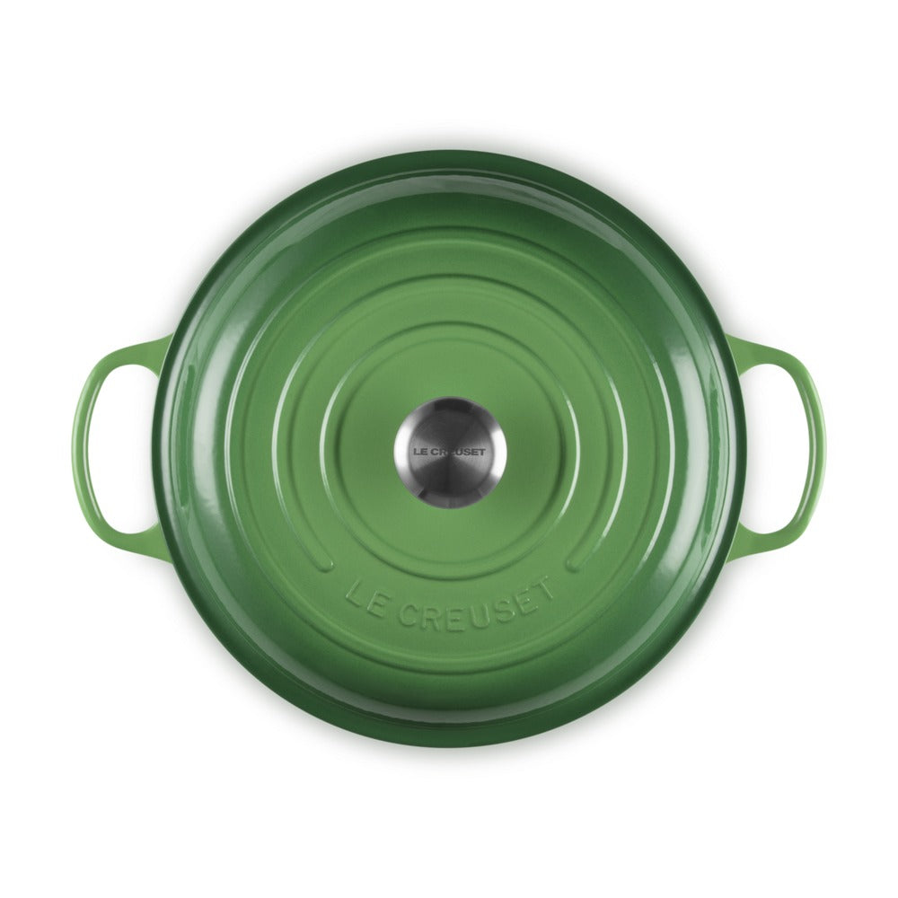 Casseruola rotonda verde con manici, in ghisa smaltata, con fondo e logo "LE CREUSET" al centro.