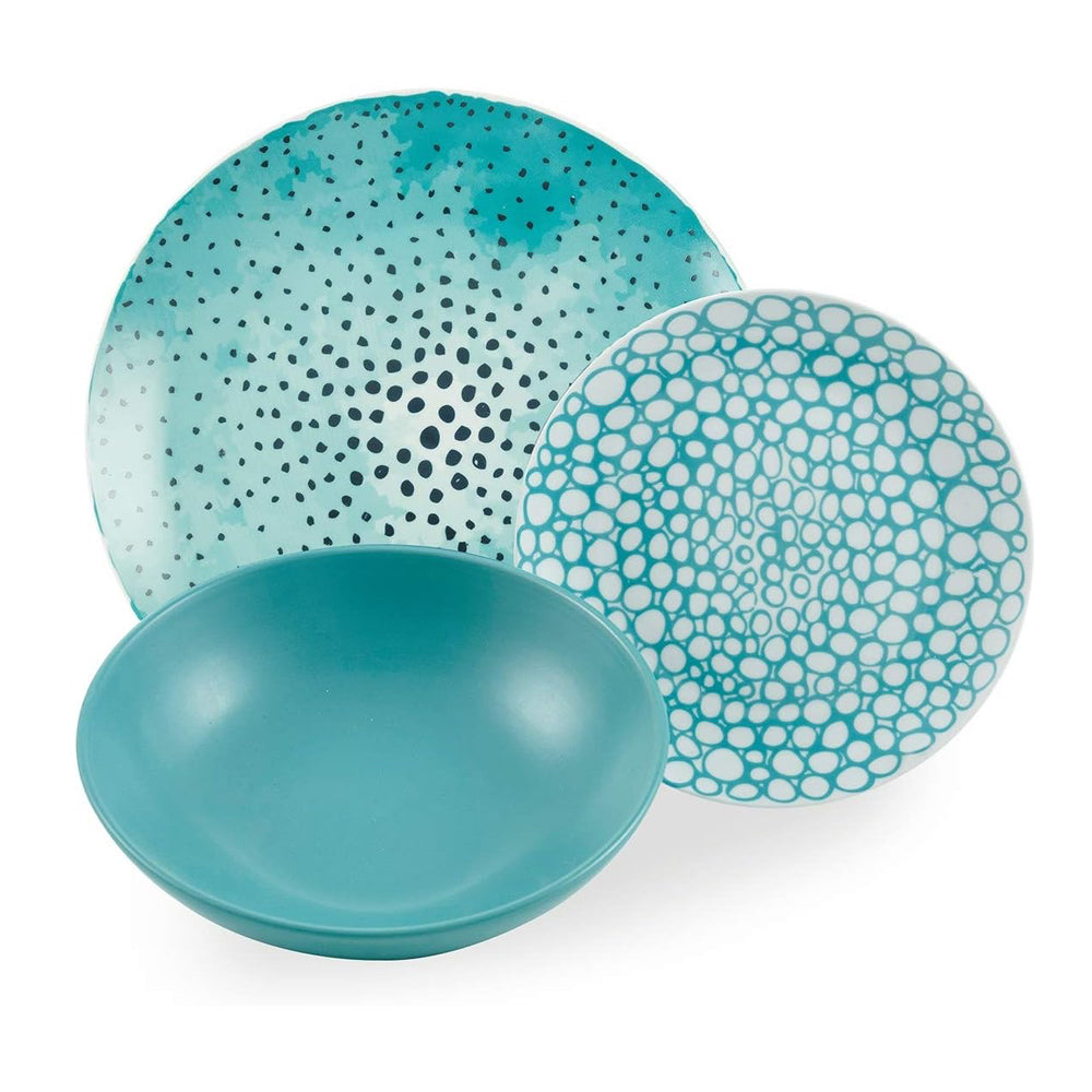 Trois assiettes en tonalités turquoise : une creuse, deux assiettes plates avec décorations de points et bulles. Fond blanc visible.