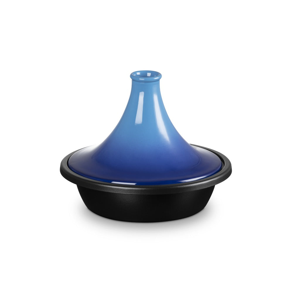 Coperchio di un tajine con forma conica, sfumature blu e base nera, in ambiente neutro.