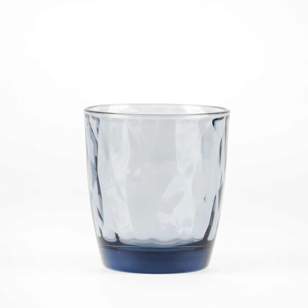 Vaso de vidrio transparentee csobre wavy shape, light gris color y base azul scuro, sobre fsobredo blanco.