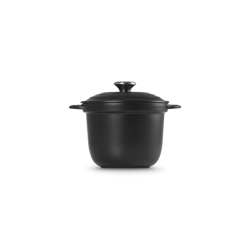 Casserole en fonte noire avec couvercle et poignée, forme ronde et surface lisse.