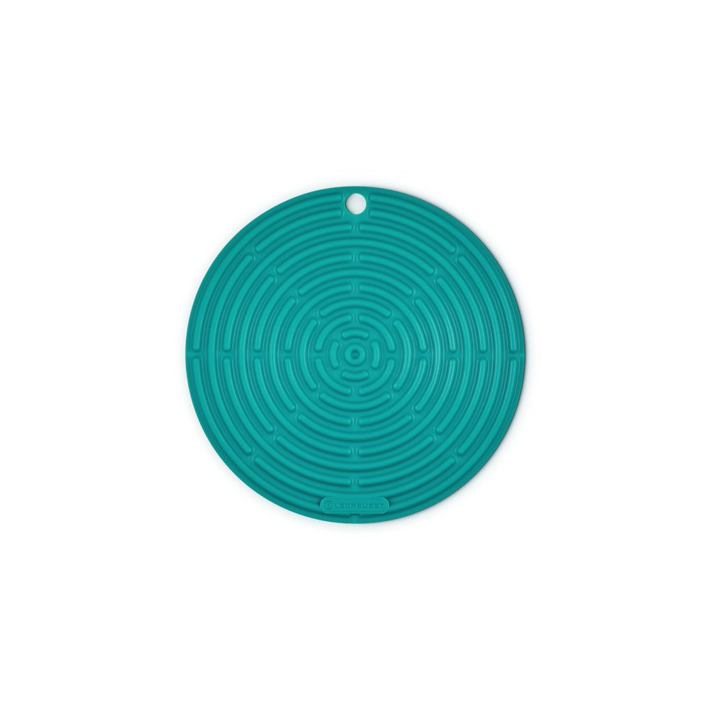 Sottopentola circolare di silicone di colore turchese con motivo a labirinto, presente uno spazio per appendere. Fondo bianco.
