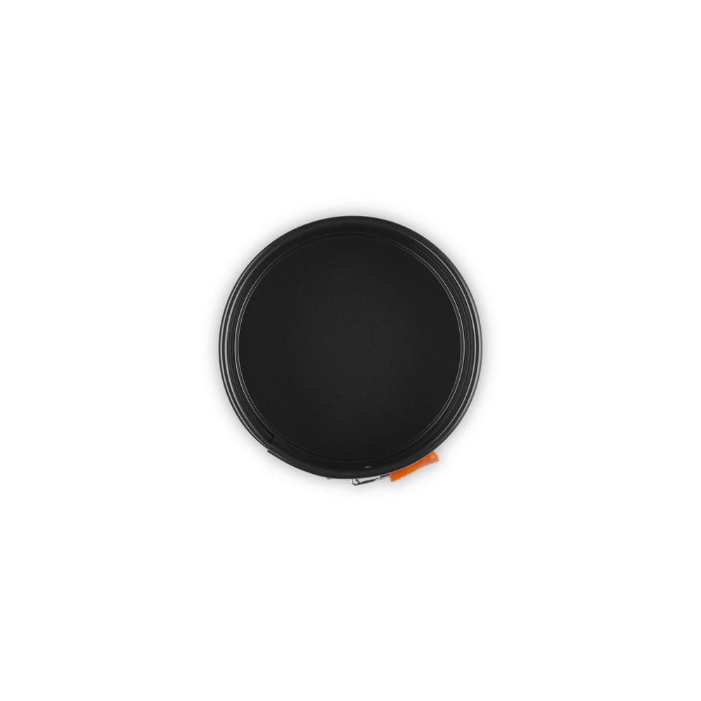 Disque circulaire noir avec bord fin et poignée orange, posé sur fond blanc.