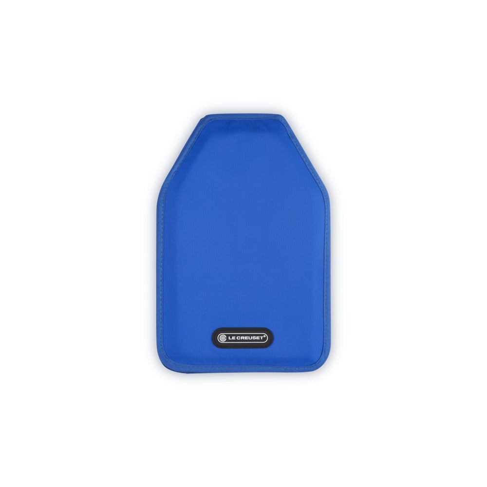Sottobicchiere blu in tessuto, sagomato con angoli arrotondati e bordo cucito, con logo "LE CREUSET" in basso. Sfondo bianco.