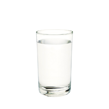 Bicchiere trasparente di vetro contenente acqua limpida su sfondo bianco.