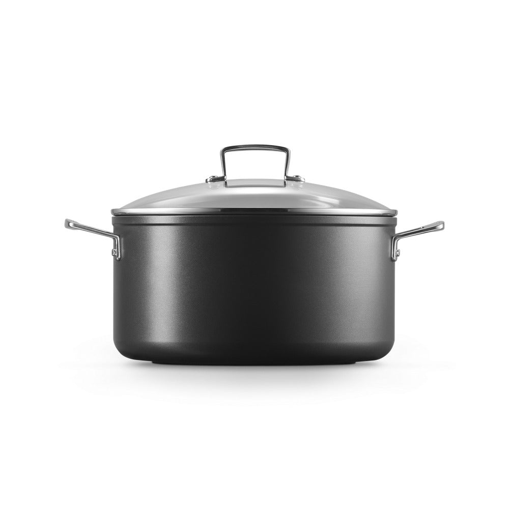 Olla negra con tapa clara y asas de acero, colocada sobre fondo blanco, sin otros objetos visibles.