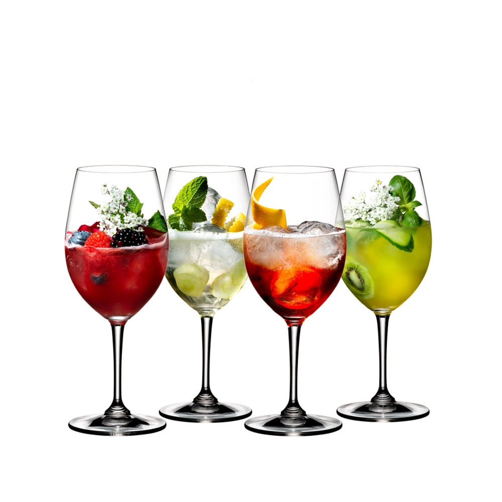 quattro calici di vino in vetro trasparente con cocktail colorati rossi, gialli, verdi e bianchi decorati con frutta, fiori ed erbe aromatiche