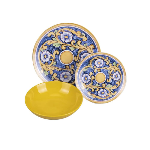 Due piatti decorati con motivi floreali blu e gialli, accompagnati da una ciotola gialla, su sfondo neutro.