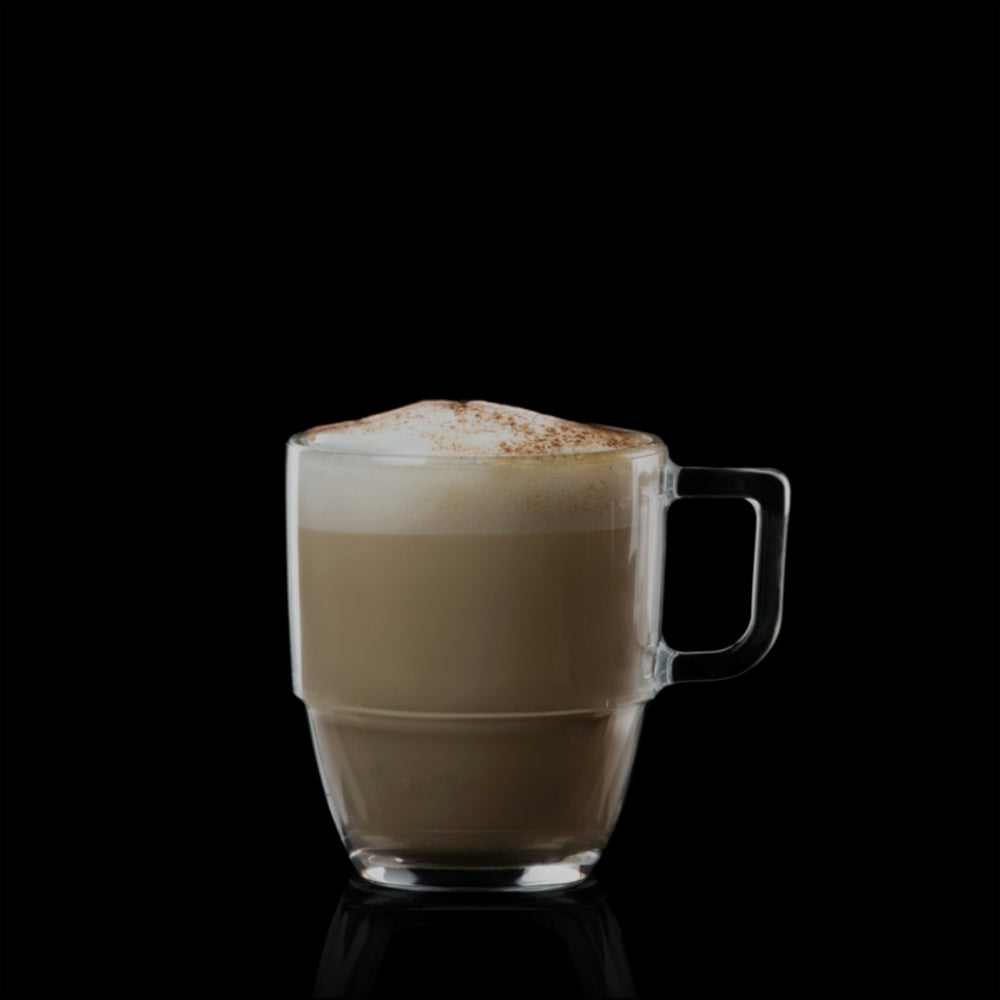 Transparante koffiemok met schuim en cacaopoeder, op zwarte achtergrond.