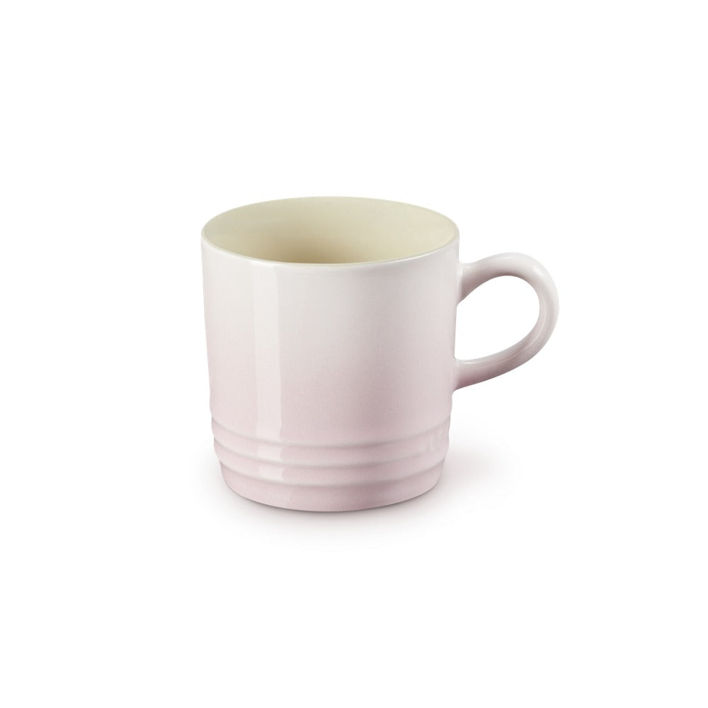 Tazza di ceramica di colore rosa chiaro, con manico laterale e base rigata, su sfondo bianco.